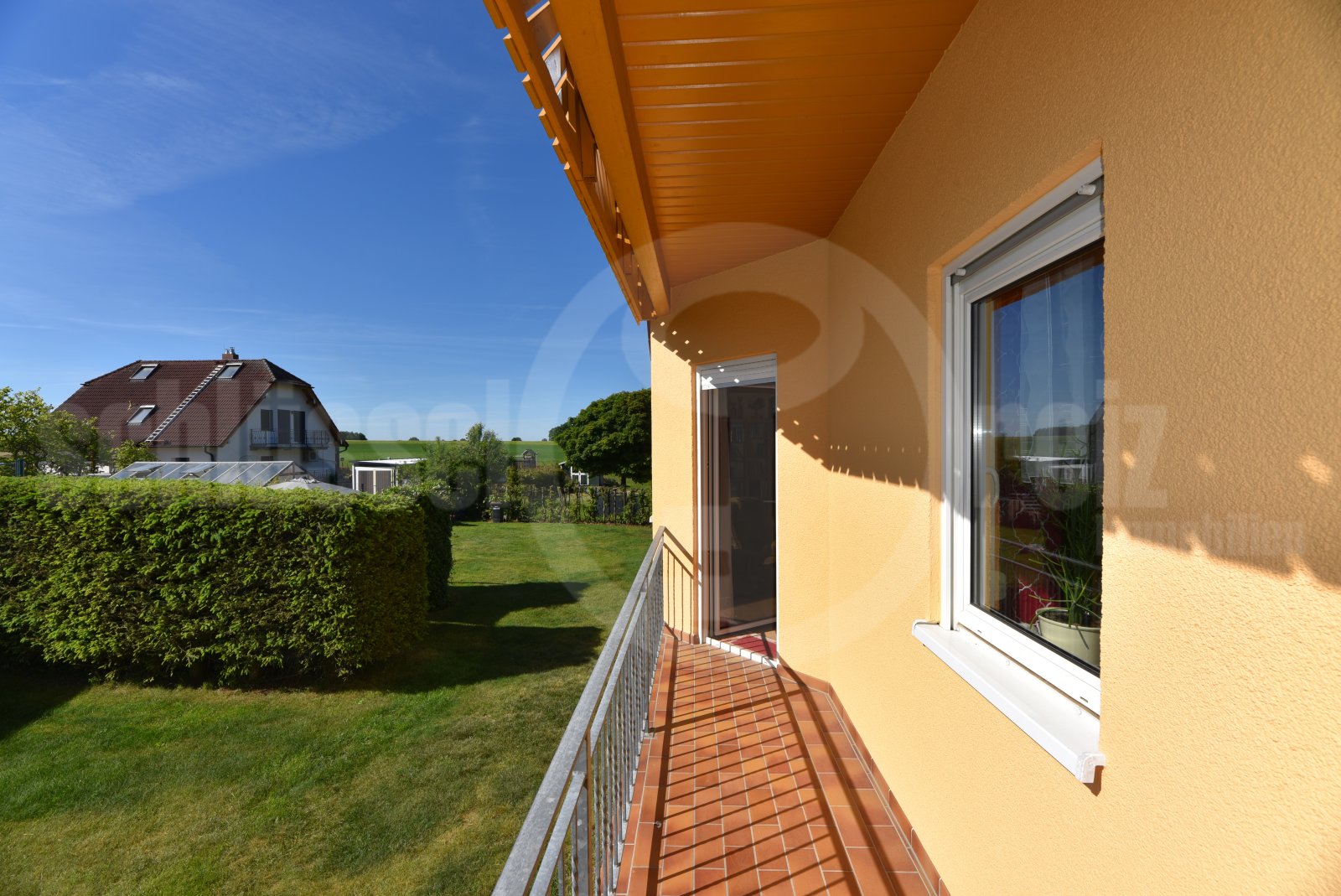 Überdachter Balkon mit Stahlgeländer und freier Gartenaussicht am WZ Überdachter Balkon mit Stahlgeländer und freier Gartenaussicht am WZ
