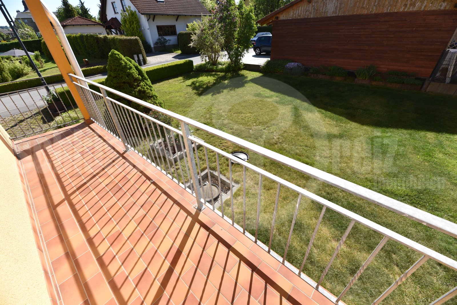 Überdachter Balkon mit Stahlgeländer und freier Gartenaussicht am WZ Überdachter Balkon mit Stahlgeländer und freier Gartenaussicht am WZ